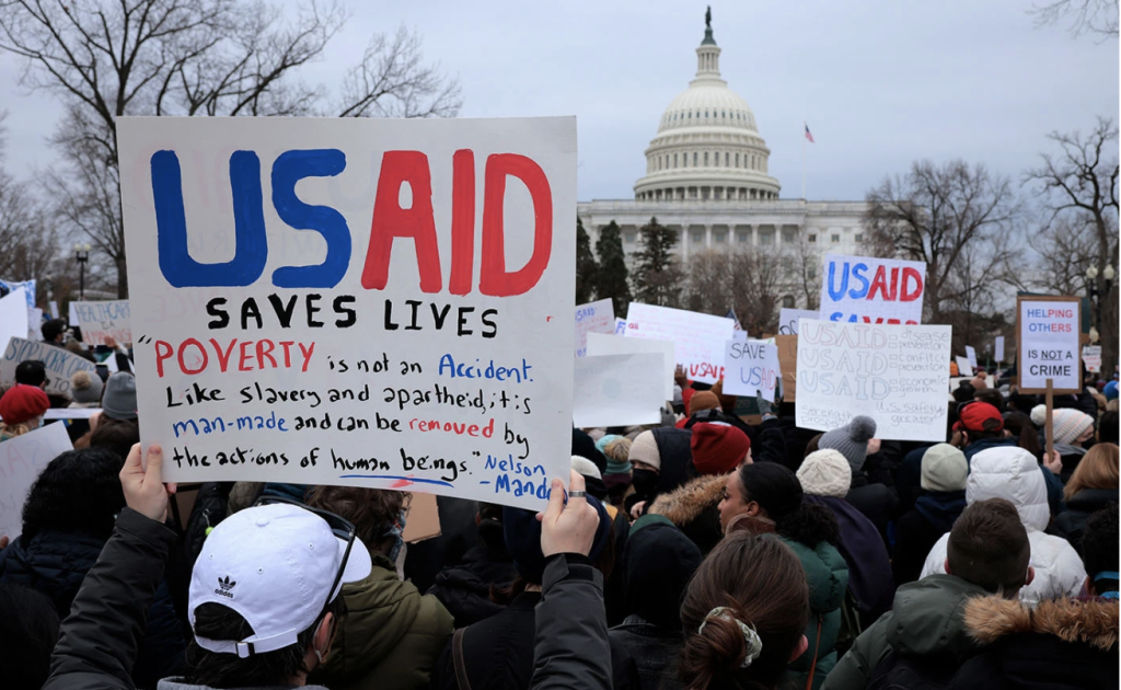 Photo of demonstration with sign that reads, "USAID Saves Lives"